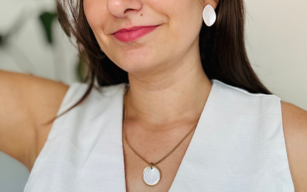 Zena nosi elegantan set nakita. Bele Minđuše i ogrlica.